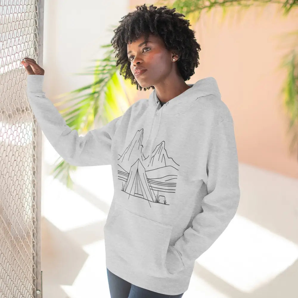 Woman wearing a white unisex hoodie with mountain and tent line art, cozy fleece, spacious kangaroo pocket