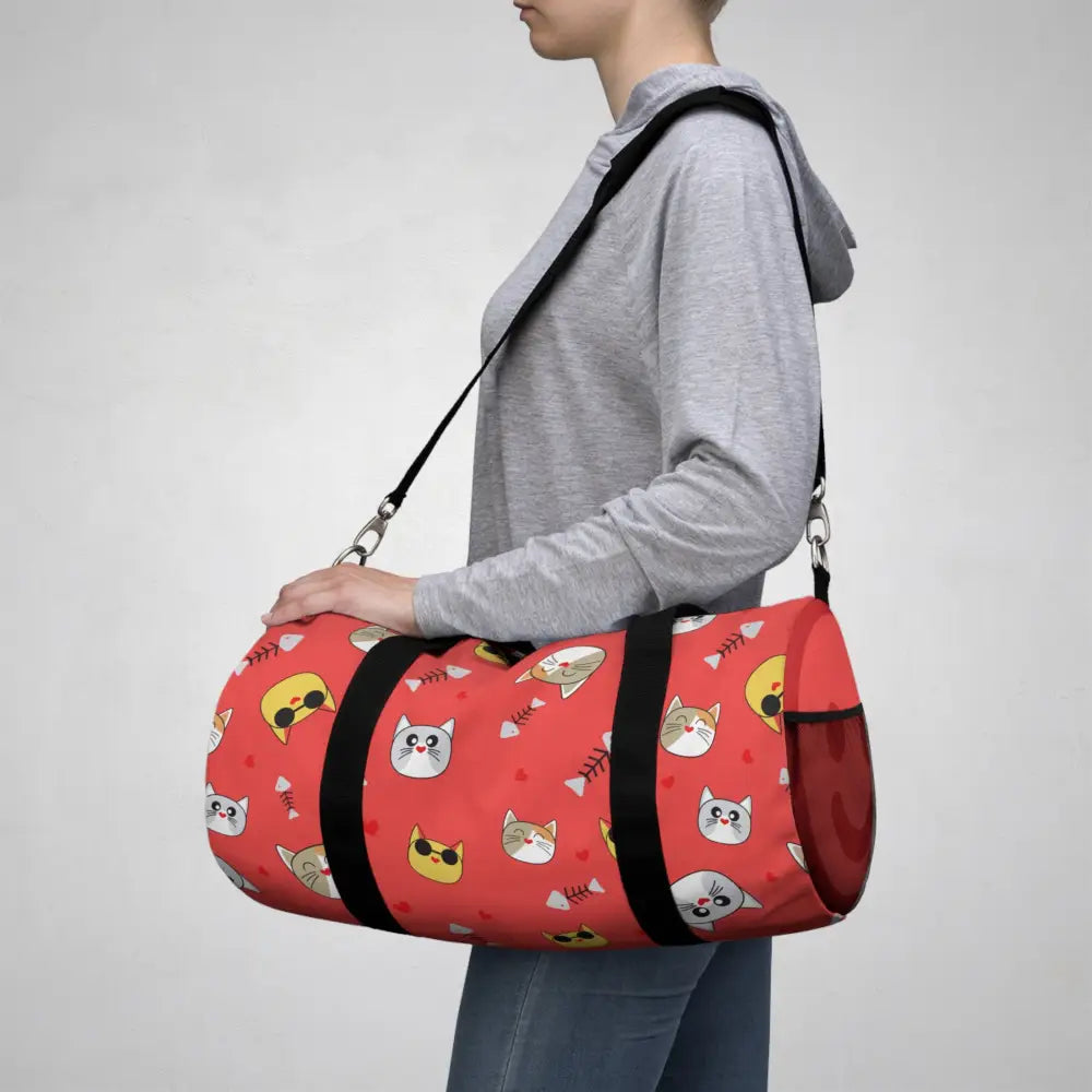Red duffel bag with cartoon cat faces and fish bones, perfect favorite travel companion