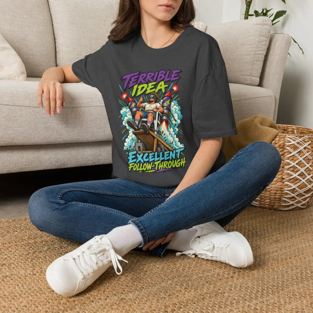 Dark gray oversized unisex t shirt with retro rocket graphic and bold purple green text care instructions low heat tumble dry