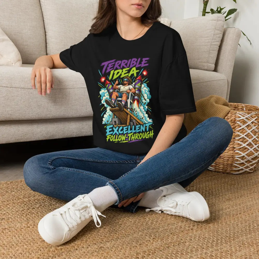 Unisex black short-sleeved t-shirt with retro rocket graphic and terrible idea excellent follow-through text low heat tumble dry care instructions